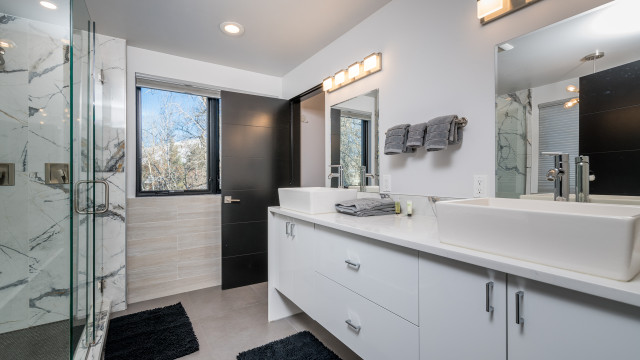 Master Bathroom exemplifies luxury with a large walk in shower, two person tub, views of the woods, double vessel sinks, and separate water closet.