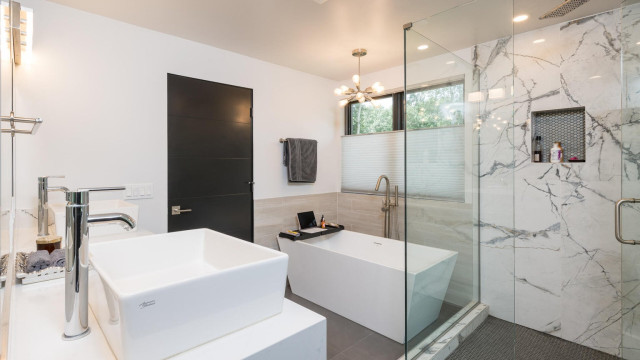 Master Bathroom exemplifies luxury with a large walk in shower, two person tub, views of the woods, double vessel sinks, and separate water closet.